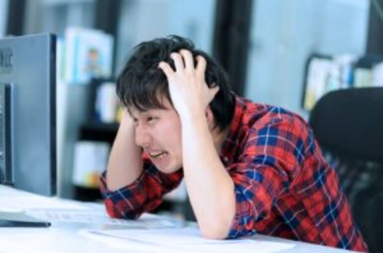 困って頭を抱えている男性